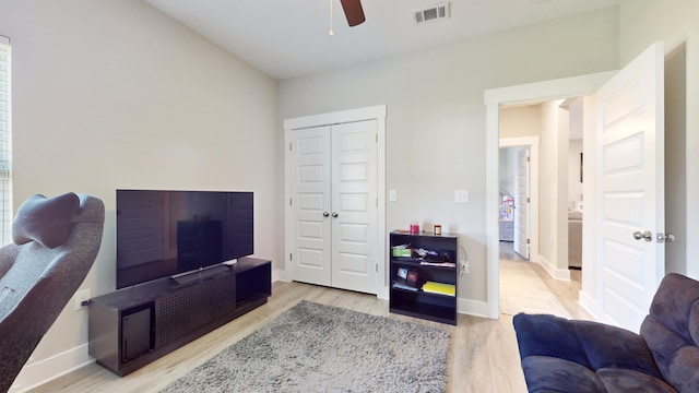 living area featuring a ceiling fan, baseboards, visible vents, and wood finished floors