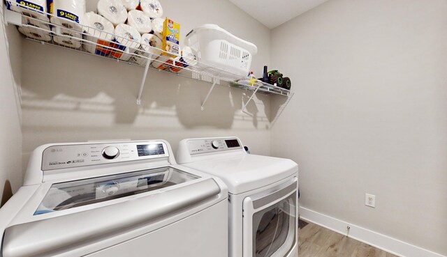 clothes washing area with laundry area, baseboards, wood finished floors, and independent washer and dryer