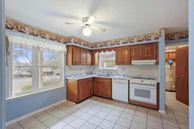 kitchen featuring white appliances, brown cabinetry, under cabinet range hood, water heater, and a sink