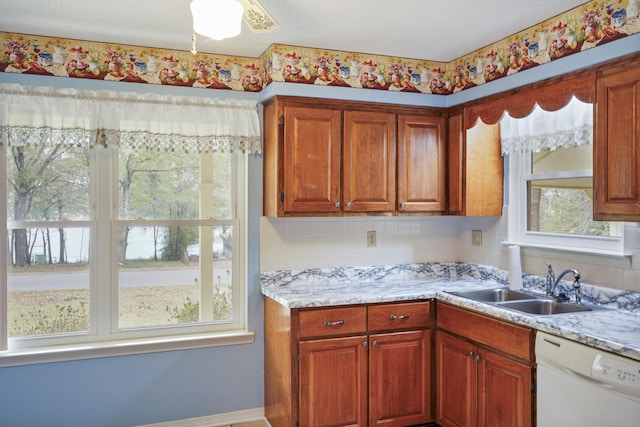 kitchen with white dishwasher, brown cabinetry, and a sink