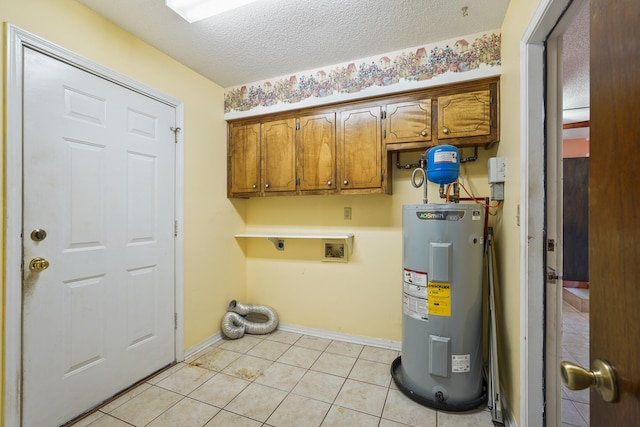 laundry area with cabinet space, electric water heater, a textured ceiling, electric dryer hookup, and light tile patterned flooring