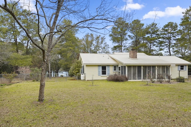 back of property with a sunroom, a chimney, fence, and a yard