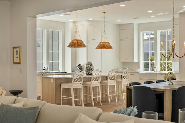 kitchen with a kitchen island, open floor plan, a kitchen bar, light countertops, and light wood-style floors