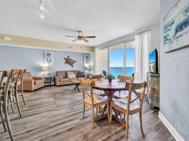 dining space featuring visible vents, a ceiling fan, a textured ceiling, light wood-type flooring, and baseboards