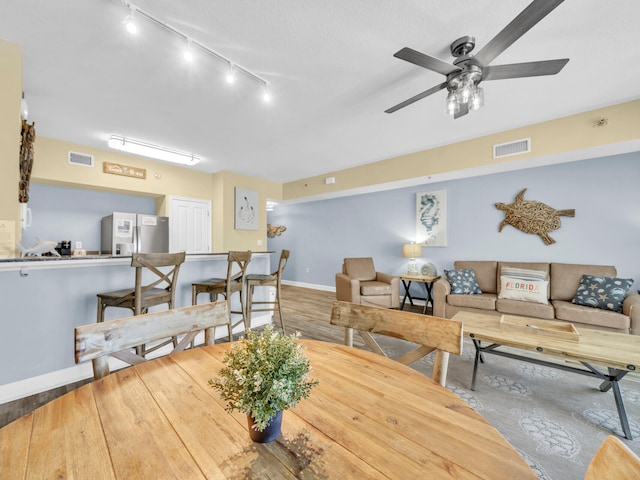 dining area with a ceiling fan, visible vents, baseboards, and wood finished floors