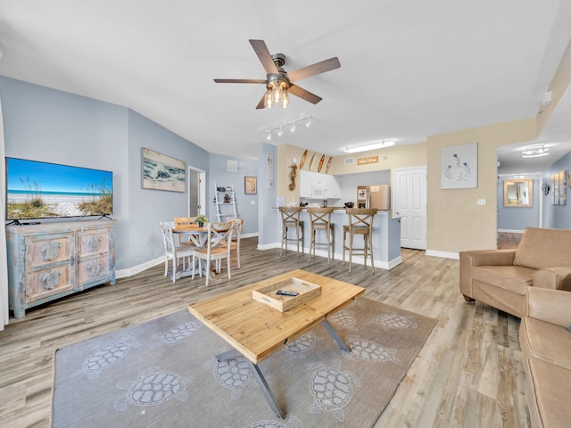 living area with track lighting, ceiling fan, baseboards, and wood finished floors