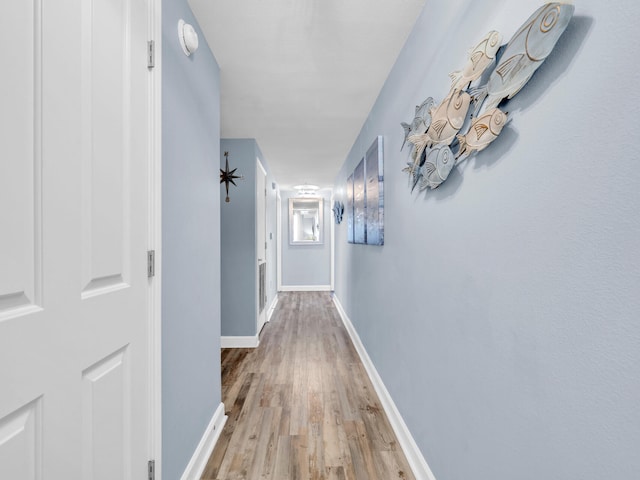 hall featuring light wood-type flooring and baseboards