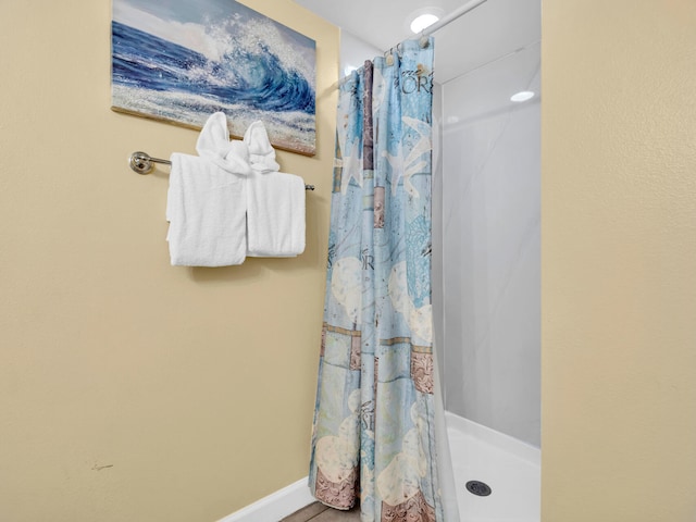 bathroom featuring a shower stall and baseboards