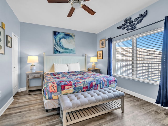 bedroom featuring a ceiling fan, baseboards, and wood finished floors