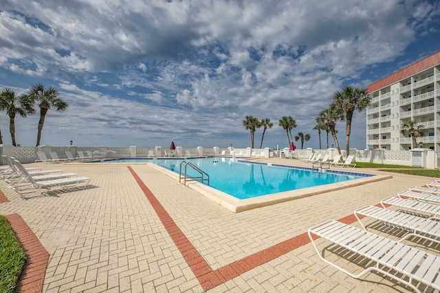 community pool featuring fence and a patio