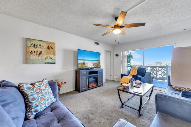 909 Santa Rosa Blvd Unit 537, Fort Walton Beach, FL 32548 - living room featuring visible vents, a textured ceiling, a glass covered fireplace, carpet floors, and ceiling fan