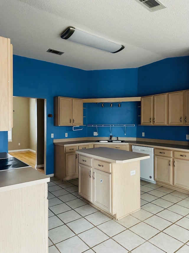 kitchen with light tile patterned floors, visible vents, white dishwasher, a sink, and light brown cabinetry