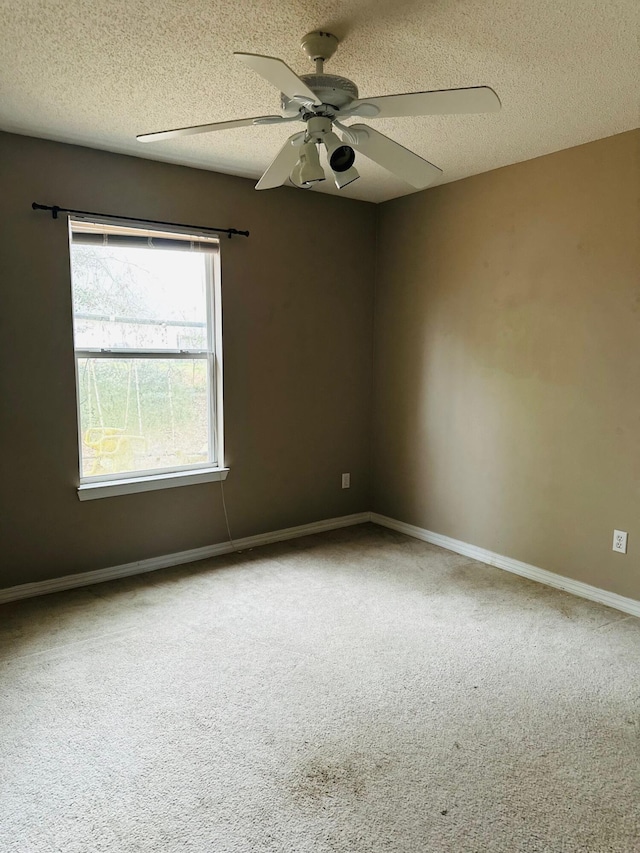 carpeted spare room featuring ceiling fan, baseboards, and a textured ceiling