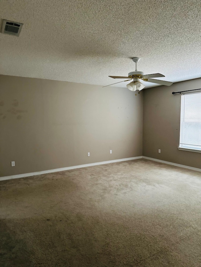 carpeted spare room featuring a ceiling fan, baseboards, visible vents, and a textured ceiling