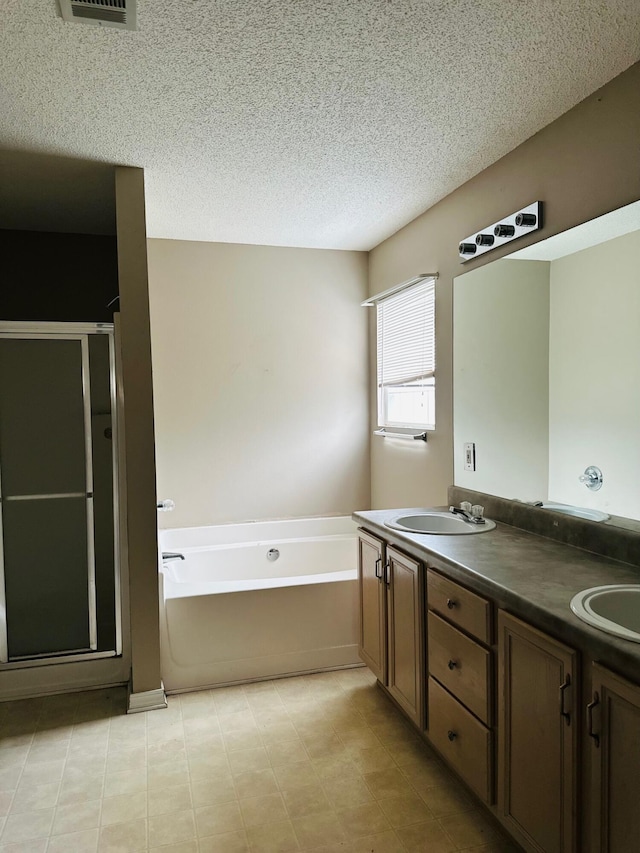 bathroom with a sink, a garden tub, a shower stall, and a textured ceiling