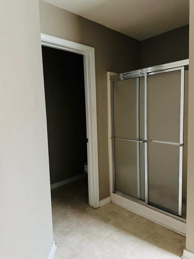 full bathroom featuring toilet, baseboards, and a stall shower