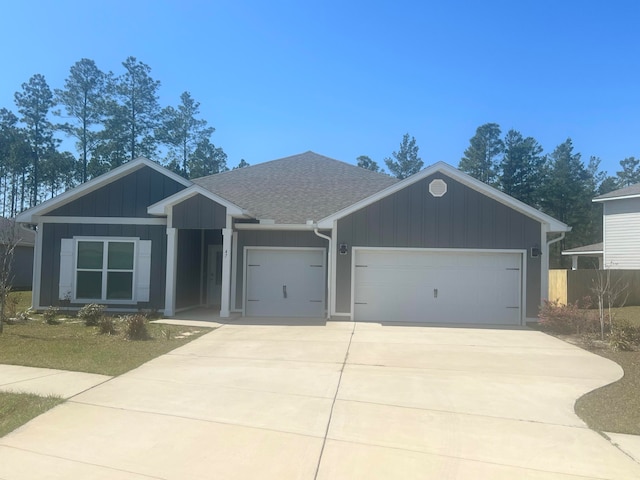 ranch-style house with a garage, board and batten siding, driveway, and roof with shingles