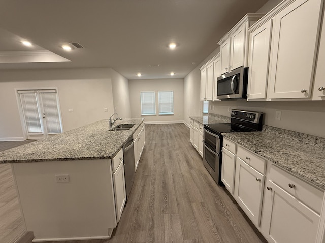 kitchen with recessed lighting, stainless steel appliances, wood finished floors, white cabinetry, and a sink