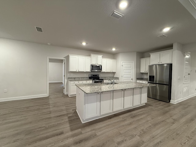 kitchen with visible vents, white cabinetry, stainless steel appliances, and a sink