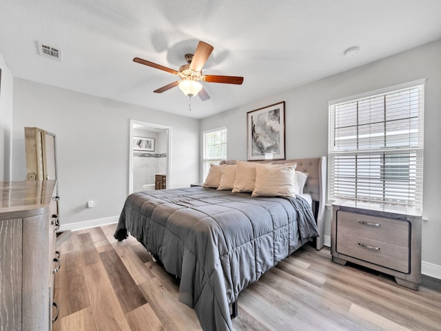 bedroom with visible vents, light wood-style flooring, baseboards, and ensuite bathroom