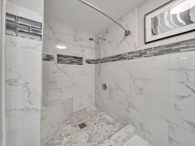 bathroom featuring a textured ceiling and tiled shower