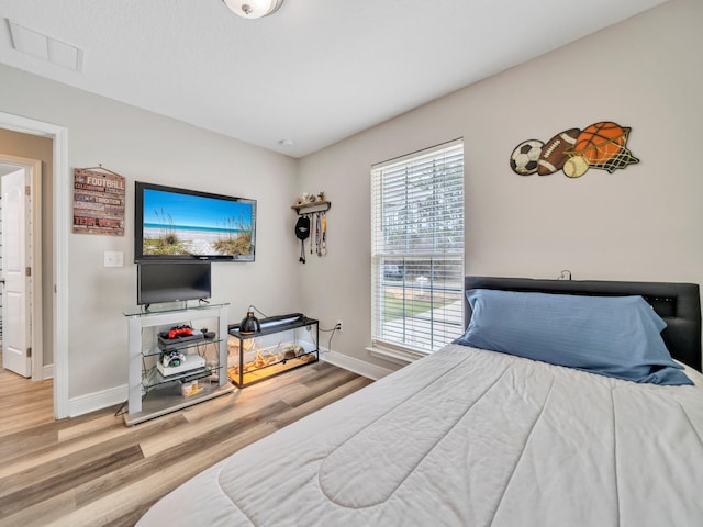 bedroom with visible vents, baseboards, and wood finished floors