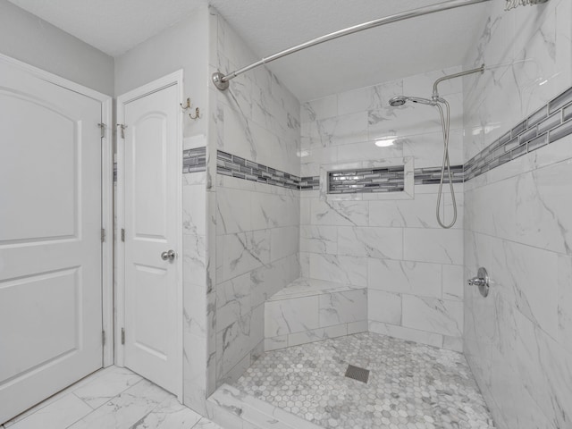 bathroom with marble finish floor and tiled shower