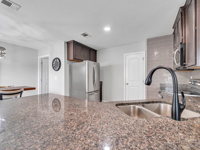 kitchen with decorative backsplash, visible vents, stainless steel appliances, and a sink