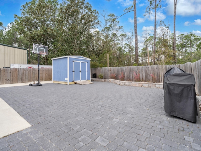 view of patio / terrace with a fenced backyard, a storage unit, area for grilling, and an outbuilding