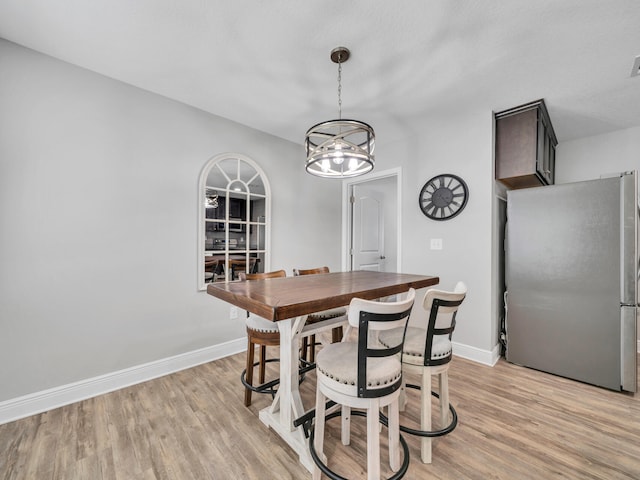 dining space with baseboards and light wood finished floors