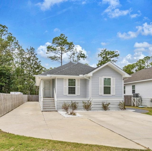 view of front of house with driveway, a shingled roof, and fence