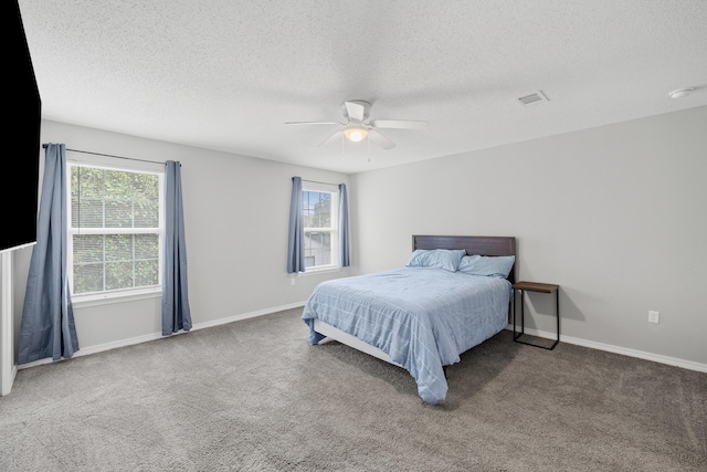 carpeted bedroom featuring baseboards, multiple windows, visible vents, and ceiling fan