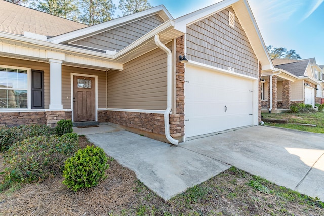 exterior space featuring stone siding, driveway, and an attached garage