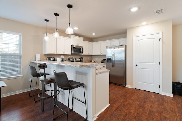 kitchen featuring visible vents, a breakfast bar, a peninsula, appliances with stainless steel finishes, and white cabinetry