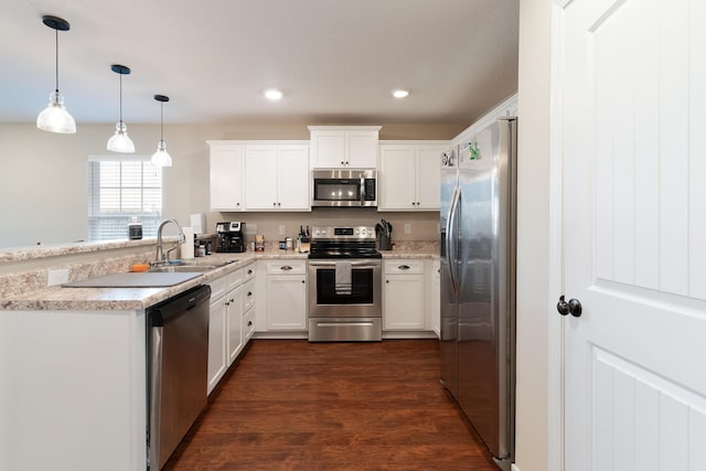 kitchen with appliances with stainless steel finishes, a peninsula, white cabinets, and light countertops