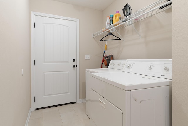 clothes washing area with laundry area, light tile patterned flooring, separate washer and dryer, and baseboards