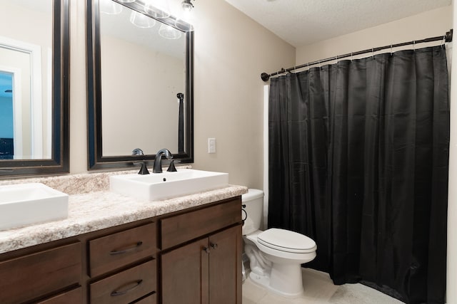 full bathroom with a textured ceiling, double vanity, toilet, and a sink