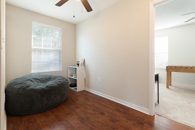 sitting room featuring carpet flooring, baseboards, wood finished floors, and a ceiling fan