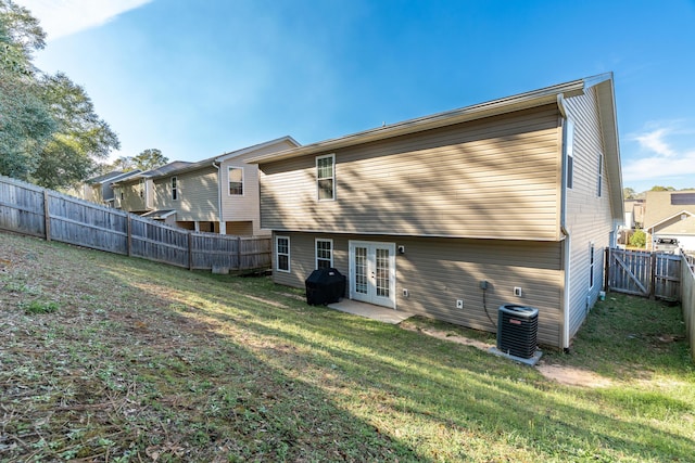 back of house featuring french doors, a lawn, central AC, and a fenced backyard