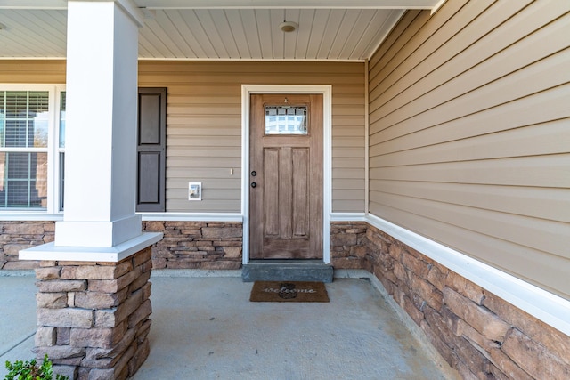 entrance to property with covered porch and stone siding