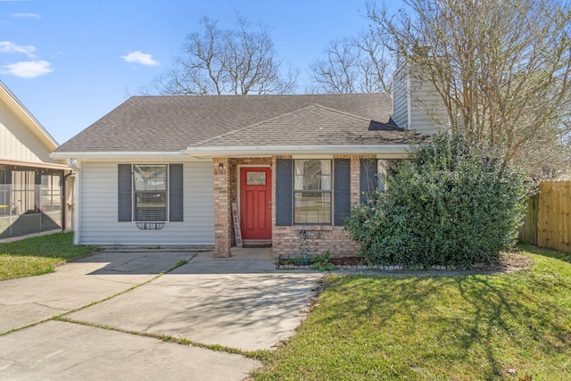 view of front of home with a chimney, roof with shingles, fence, a front lawn, and brick siding