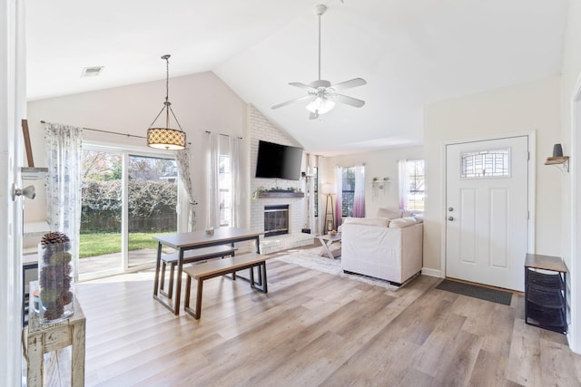 living area featuring ceiling fan, light wood-style floors, a fireplace, and a healthy amount of sunlight