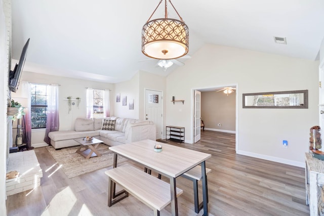 living room featuring light wood-style floors, visible vents, baseboards, and high vaulted ceiling