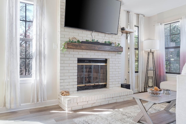 living area featuring a brick fireplace, wood finished floors, and baseboards