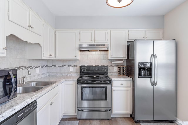 kitchen featuring under cabinet range hood, a sink, white cabinetry, appliances with stainless steel finishes, and backsplash