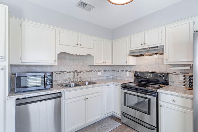 kitchen featuring white cabinets, decorative backsplash, appliances with stainless steel finishes, under cabinet range hood, and a sink