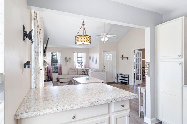 kitchen featuring ceiling fan, open floor plan, wood finished floors, light countertops, and white cabinetry