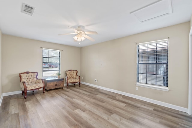 sitting room with attic access, light wood-type flooring, visible vents, and baseboards