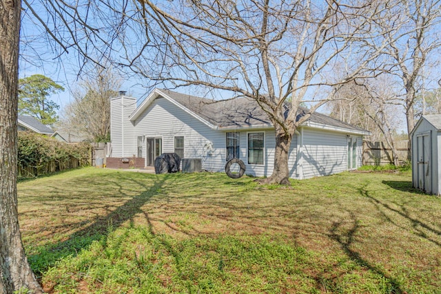 back of property featuring an outbuilding, fence, a yard, a shed, and a chimney