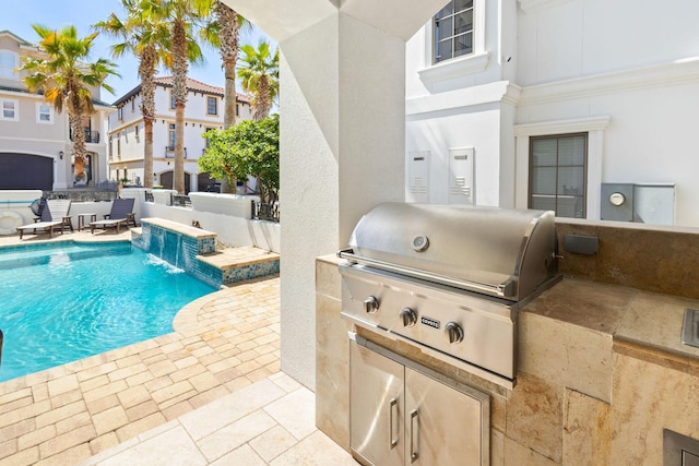 pool with an outdoor kitchen, a patio area, fence, and grilling area